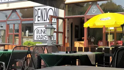 an empty restaurant with tables and a yellow umbrella at Bunkr Karlštejn - Modrý dům in Karlštejn