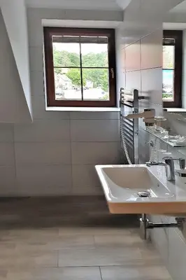 a white bathroom with two sinks and a window at Bunkr Karlštejn - Modrý dům in Karlštejn