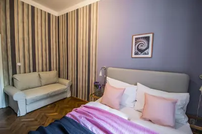 a bedroom with a bed with pink pillows and a chair at 3BDR City Center Ruterra Apartment in Prague