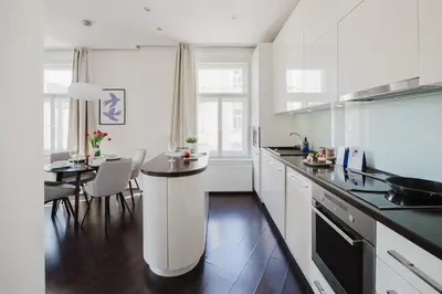 a white kitchen with a table and a dining room at Prague Days - Open-plan Apartment with Netflix in Žižkov in Prague