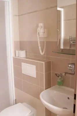 a bathroom with a toilet and a phone on the wall at Hotel Klara in Prague