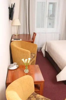 a hotel room with a table and chairs and a bed at Hotel Klara in Prague