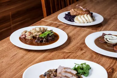 four plates of food on a wooden table at Penzion Marjána in Mníšek pod Brdy