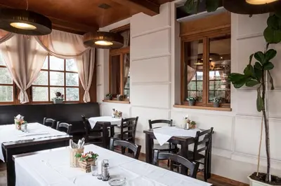 a restaurant with white tables and chairs and windows at Penzion Marjána in Mníšek pod Brdy