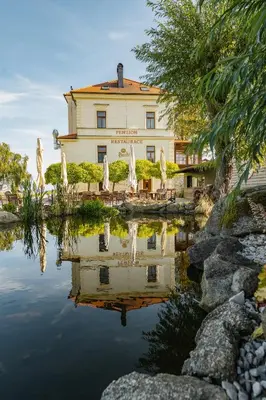 a building with a reflection in the water in front at Penzion Marjána in Mníšek pod Brdy