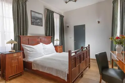 a bedroom with a bed and a desk and a chair at Hotel At the Green Grape in Prague