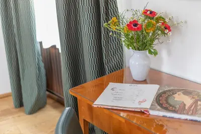 a vase of flowers on a wooden table with a vase at Hotel At the Green Grape in Prague