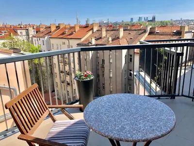 a table and chairs on a balcony with a view at CE Apartment Prague Castle in Prague
