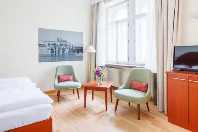 a bedroom with two chairs and a tv and a bed at Hapimag Apartments Prague in Prague