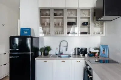 a kitchen with a black refrigerator and white cabinets at Romantic designer apartment Prague in Prague