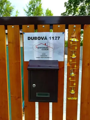 a sign on a wooden fence with a mailbox at Apartmán Dubová in Milovice