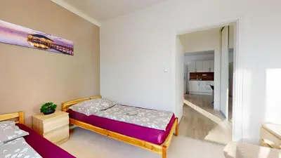 a small bedroom with a bed and a room with a kitchen at Apartmán Dubová in Milovice