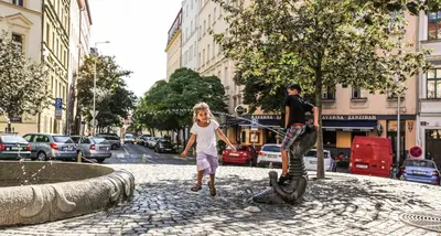 a street with tables and cars parked on the street at Hotel Orion in Prague