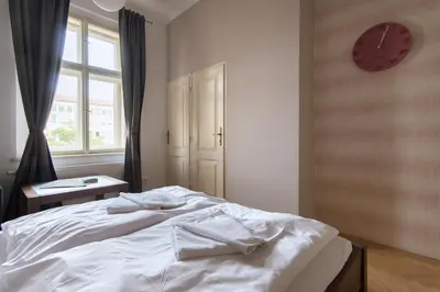 a bedroom with a white bed with a clock on the wall at Great place near city centre in Prague