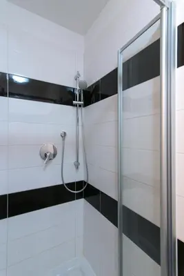 a shower in a bathroom with black and white tiles at Great place near city centre in Prague