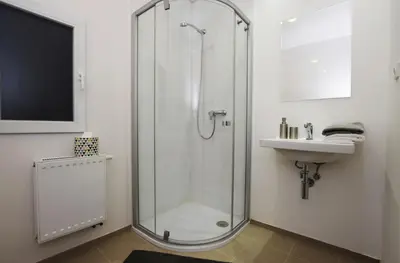 a bathroom with a glass shower and a sink at Císařka Apartments in Prague