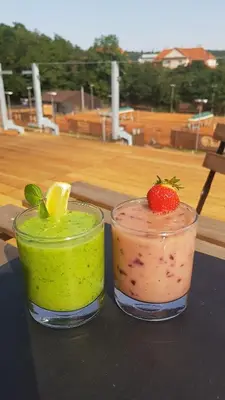 two cocktails sitting on top of a table with a strawberry at Sport Pension Cibulka in Prague