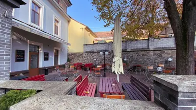 a patio with red benches and tables and chairs at Hotel Sýkora in Křivoklát