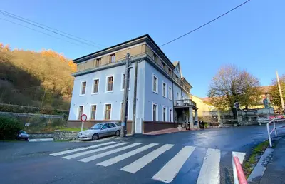 a white building with a car parked on the street at Hotel Sýkora in Křivoklát