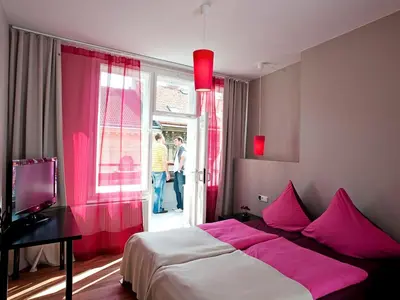 a bedroom with a bed with pink sheets and a window at Hotel PurPur in Prague