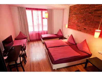 a room with two beds and a table and chairs at Hotel PurPur in Prague