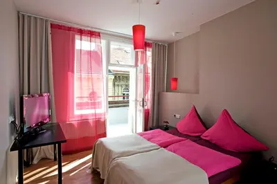 a bedroom with a bed with pink pillows and a window at Hotel PurPur in Prague