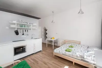 a white bedroom with a bed and a kitchen at LOVELY Prague Apartment in Prague