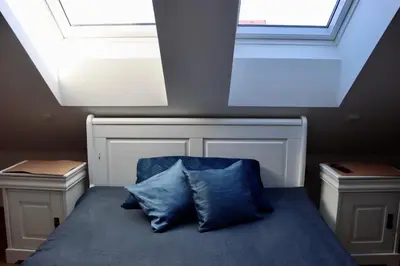 a bed with two blue pillows in a room with skylights at Penzion U Kapra in Roudnice nad Labem