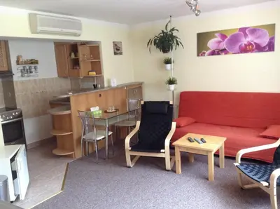 a living room with a red couch and a kitchen at Penzion Chaloupka in Prague