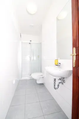 a white bathroom with a toilet and a sink at Hostel Little Quarter in Prague