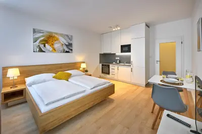 a bedroom with a bed and a desk and a kitchen at CityWest Apartments in Prague
