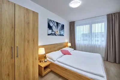 a bedroom with a bed and a large window at CityWest Apartments in Prague