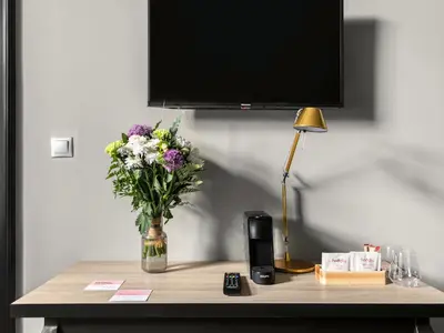 a vase of flowers on a table with a tv at Numa Prague Root in Prague