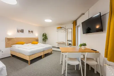 a bedroom with a bed and a table and a tv at Self-service Hotel Ostaš Praha in Prague