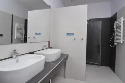 a white bathroom with two sinks and a shower at Pension Milk Inn in Prague