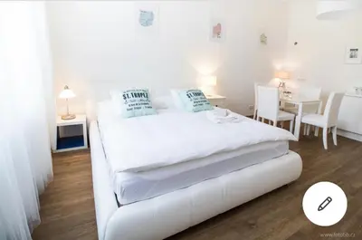 a white bedroom with a white bed and a table at Romantic Apartment Petra - free parking Friday-Sunday in Prague