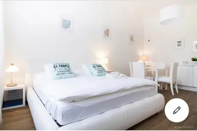 a white bedroom with a white bed and a table at Romantic Apartment Petra - free parking Friday-Sunday in Prague