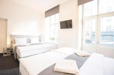 a hotel room with three beds and a tv at Narodni Stay in Prague
