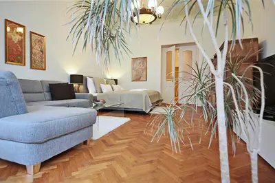 a living room with a couch and a palm tree at Apartment in the heart of Prague in Prague
