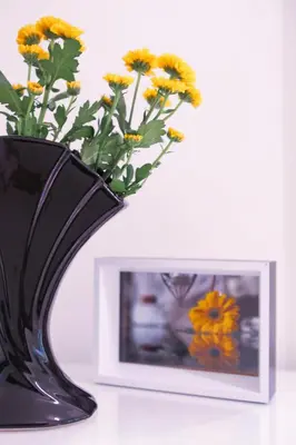 a black vase with yellow flowers next to a picture at Yellow apartment few steps from metro in Prague