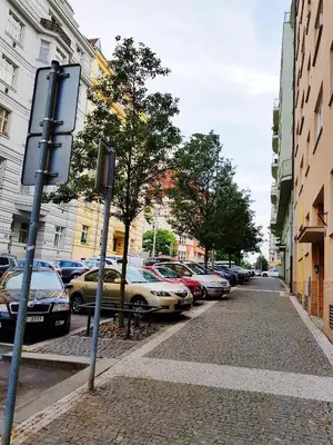 a street with cars parked on the side of the road at Yellow apartment few steps from metro in Prague