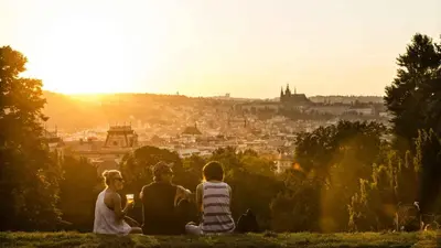three people sitting on a hill looking at a city at Spacious apartment near Wenceslas Square in Prague