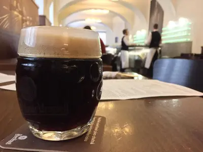 a glass of beer sitting on top of a table at Old Town Basement in Prague