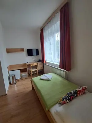 a bedroom with a green bed and a window at Hotel Garni Rambousek in Prague
