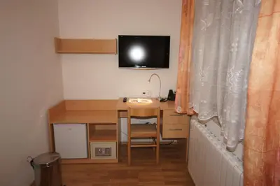 a small room with a desk and a tv on the wall at Hotel Garni Rambousek in Prague