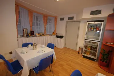 a dining room with a white table and blue chairs at Hotel Garni Rambousek in Prague