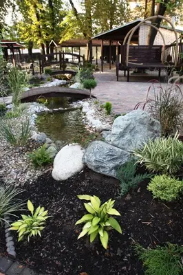 a garden with a pond and a park bench at Hotel Braník in Prague