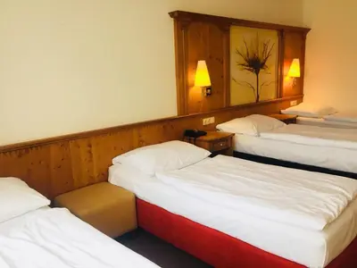 a hotel room with three beds and a mirror at Hotel Braník in Prague