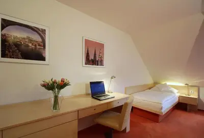 a bedroom with a desk with a laptop and a bed at Hotel DAP in Prague