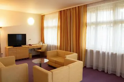 a hotel room with a desk and chairs and a television at Hotel DAP in Prague